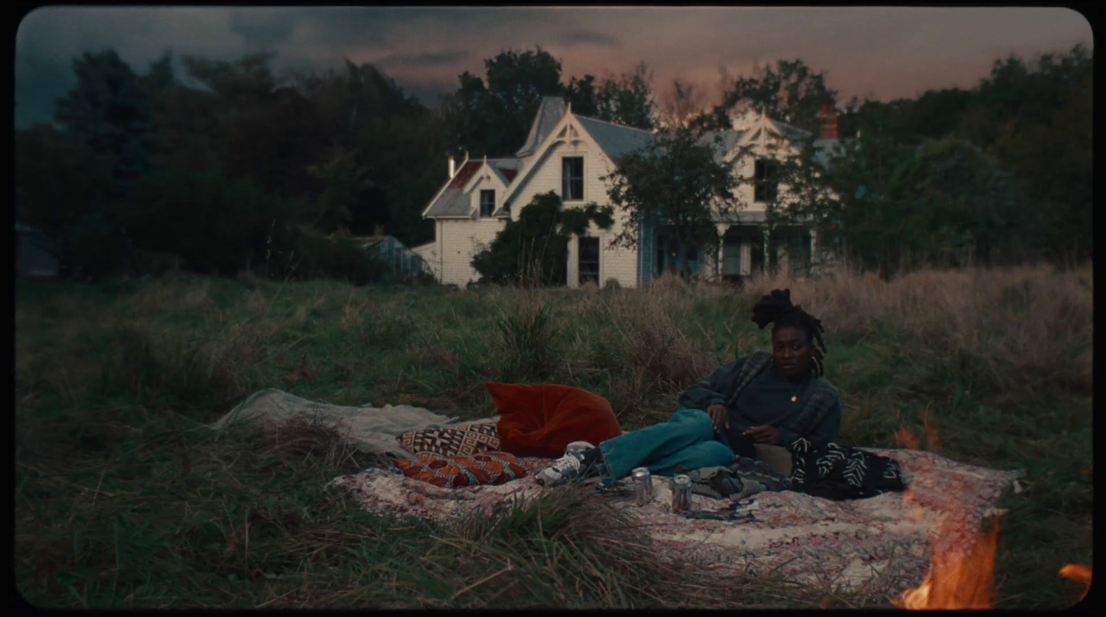 a woman sitting on a blanket in front of a house