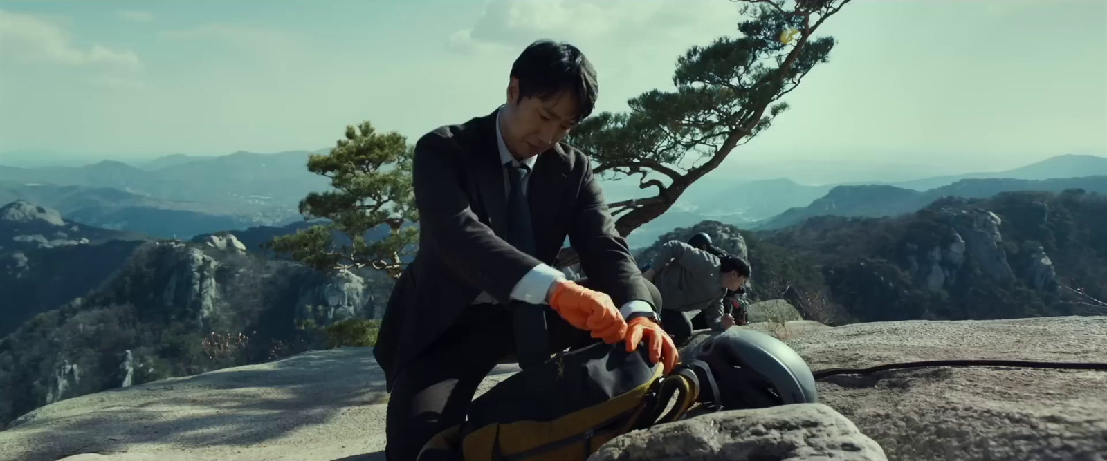 a man in a suit and tie standing on top of a mountain