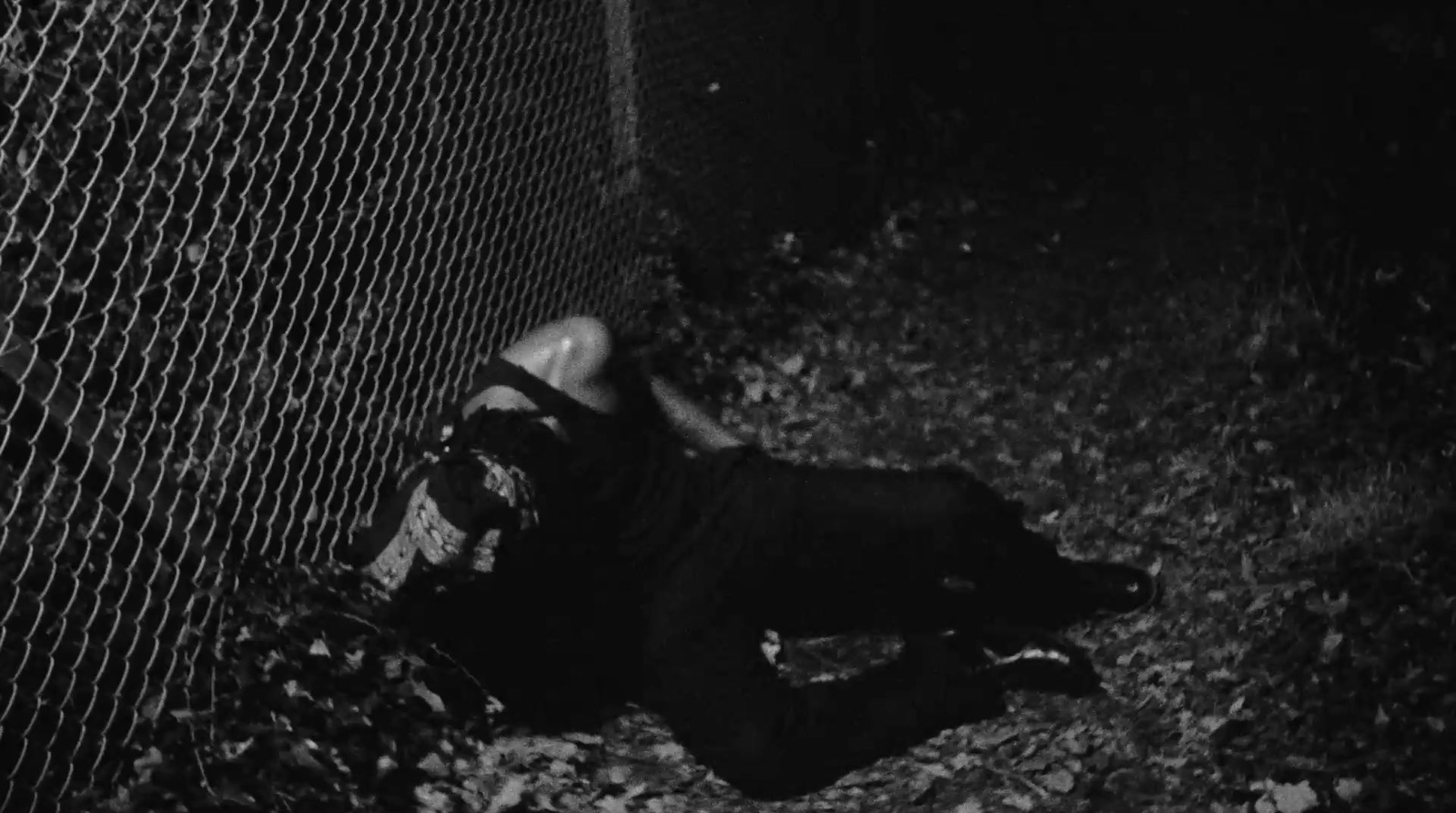 a man laying on the ground next to a fence