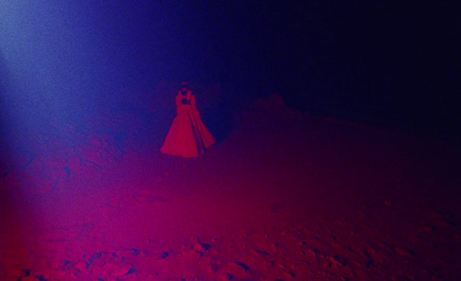 a woman in a red dress standing in a dark room