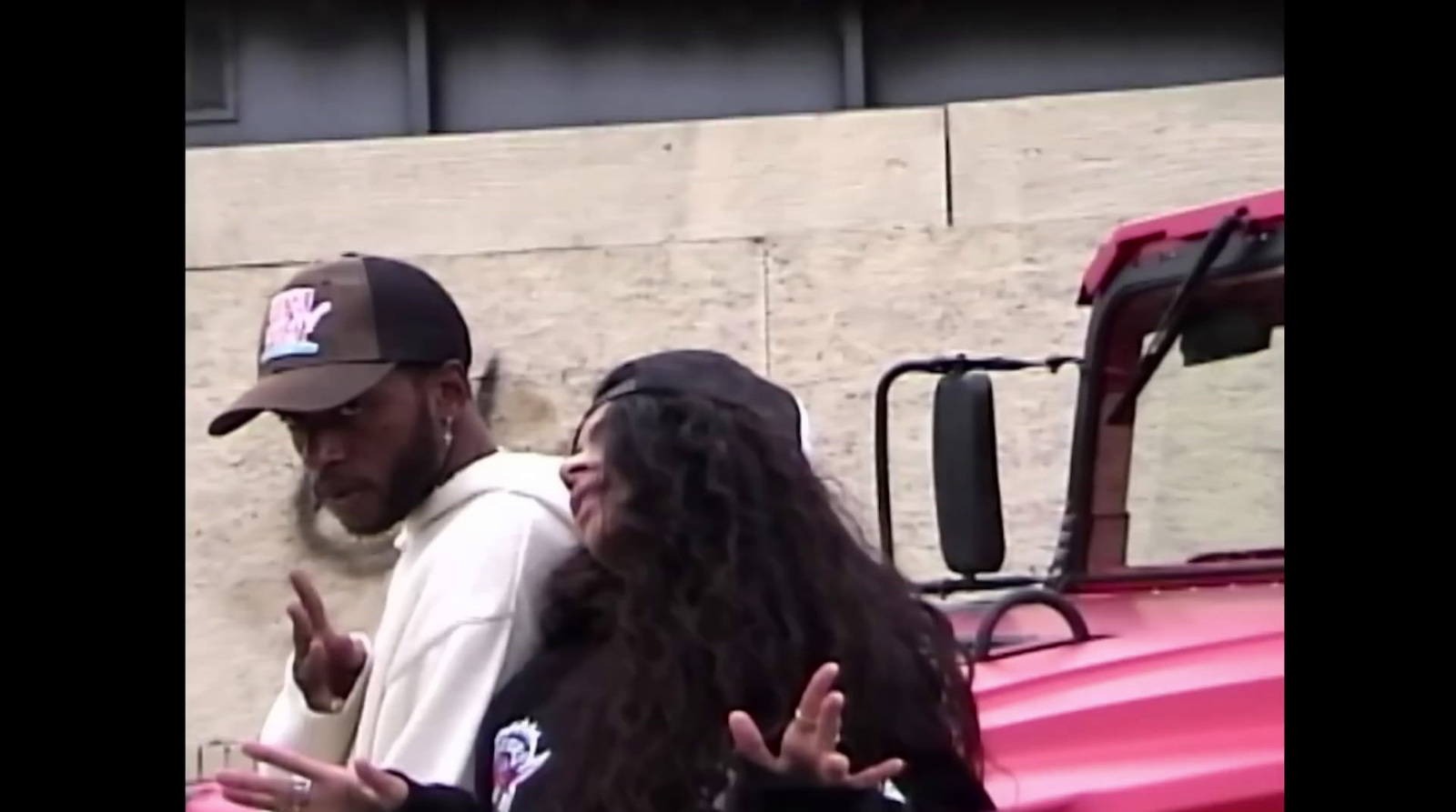 a man standing next to a woman in front of a red truck