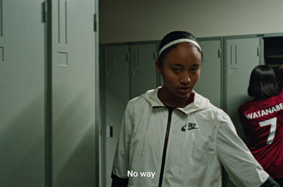 a girl in a white jacket standing in a locker