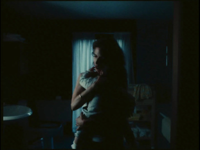 a woman holding a baby in a dark room