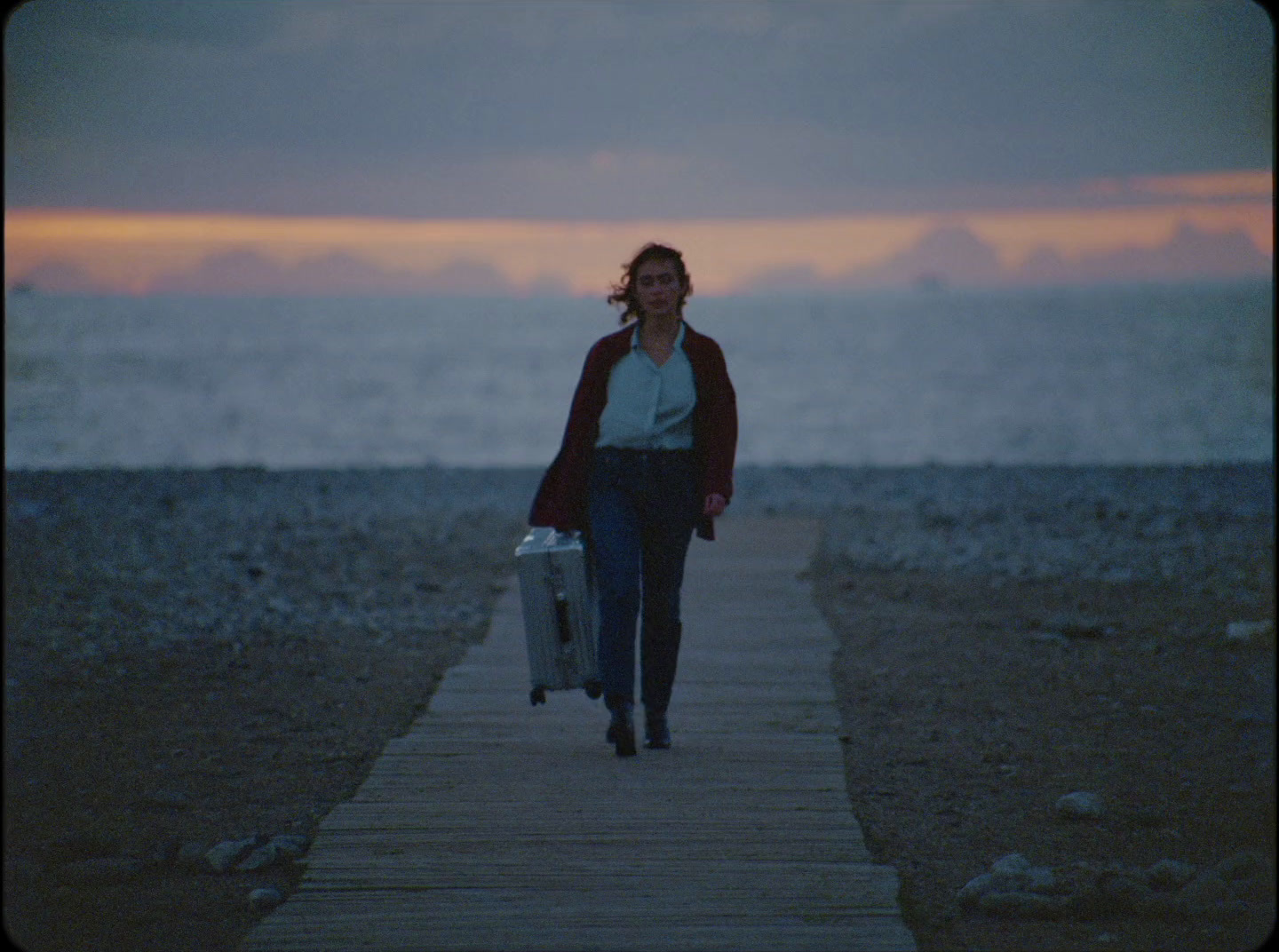 a woman walking down a wooden walkway with a suitcase