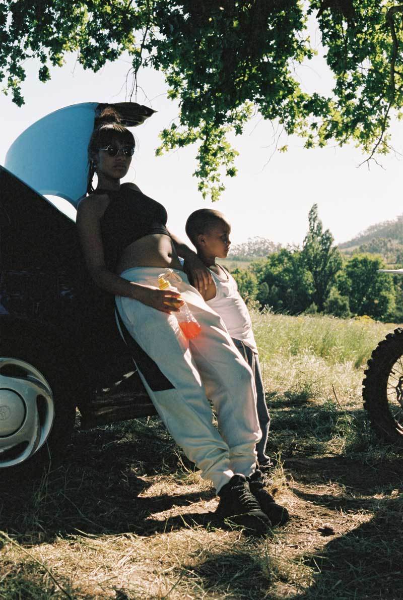 a man and a woman standing next to a car under a tree