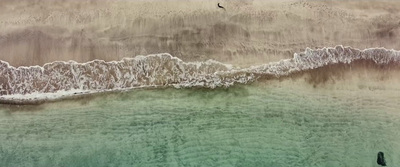 an aerial view of a beach with a wave coming in