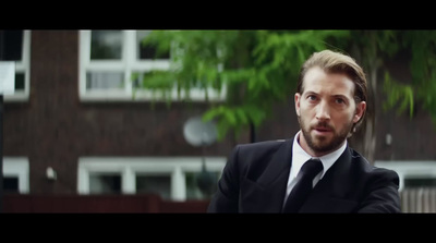 a man in a suit and tie standing in front of a building