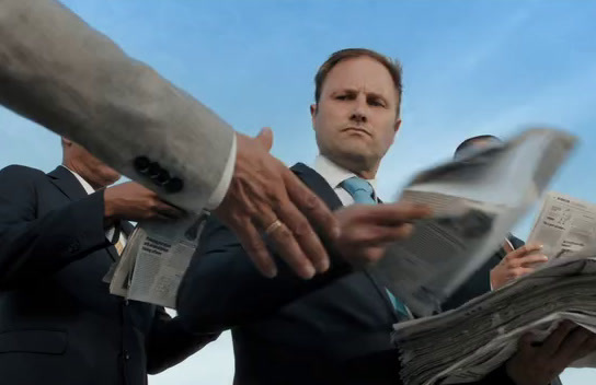 a man in a suit and tie holding newspapers