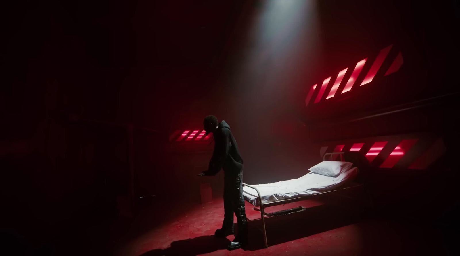 a man standing next to a bed in a dark room