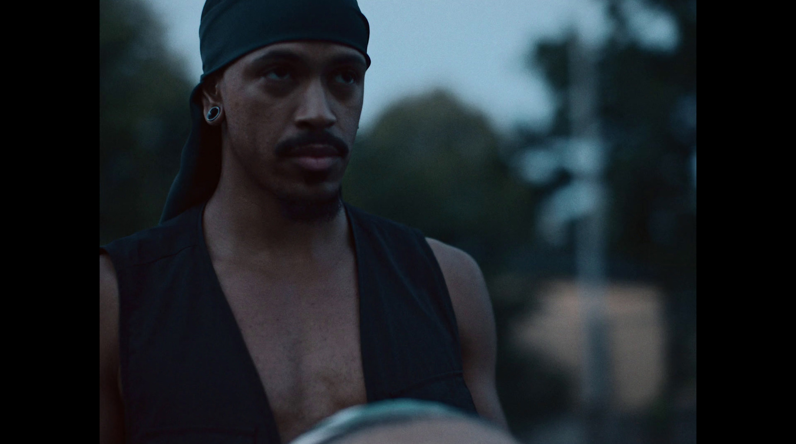 a man wearing a black tank top and a hat