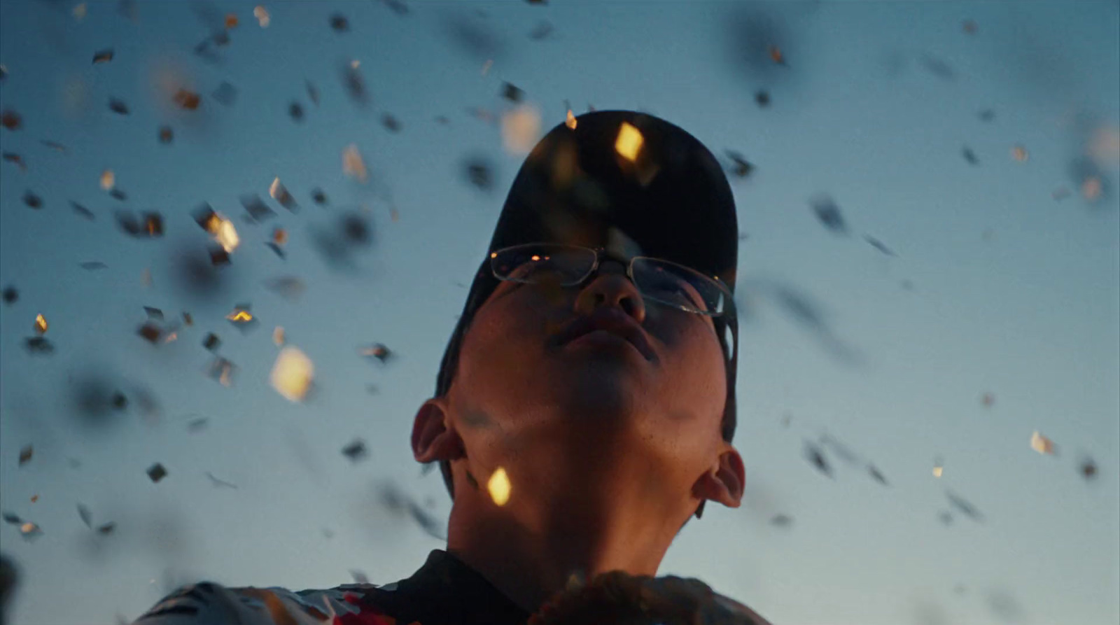 a man wearing glasses and a baseball cap looks up into the sky