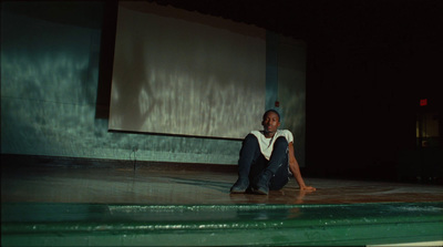 a woman sitting on the ground in front of a projection screen