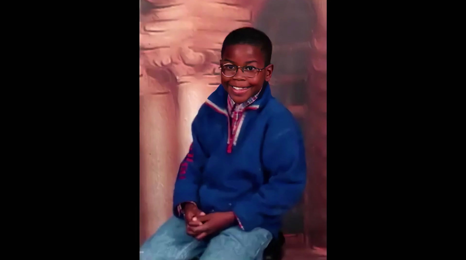 a young boy wearing glasses and a blue jacket