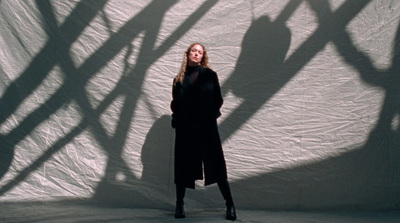 a woman standing in front of a white wall