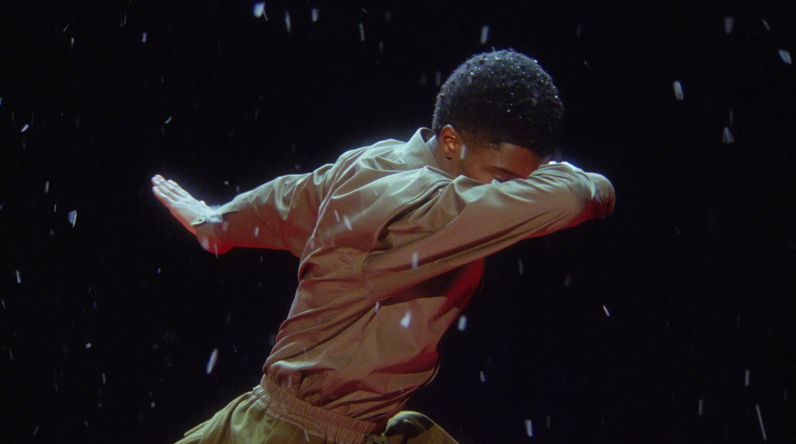 a man in a red shirt and tan pants is dancing in the snow