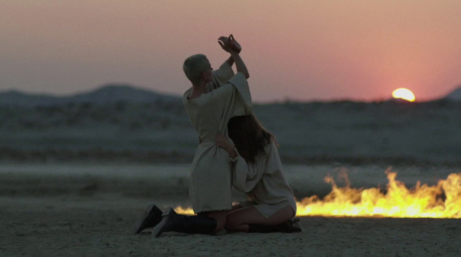 a man kneeling down next to a woman on a beach