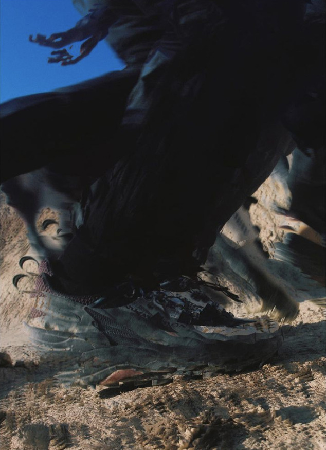 a large bird flying over a sandy beach