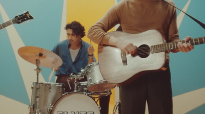 a man holding a guitar while standing next to another man