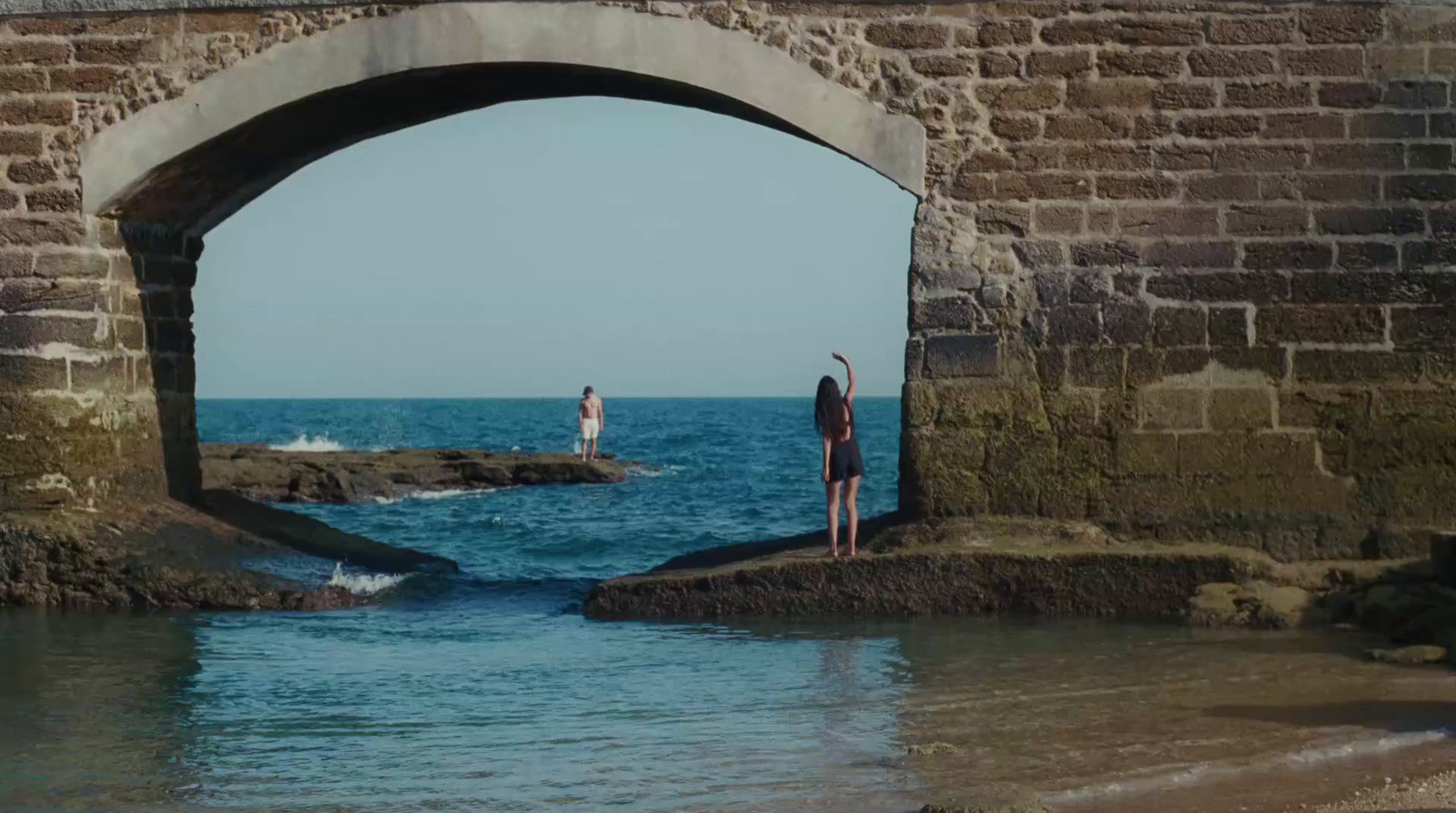 a couple of people standing on top of a stone bridge