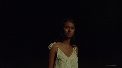 a woman standing in the dark in a white dress