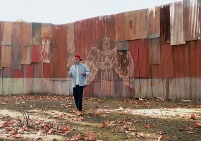 a man standing in front of a wooden wall