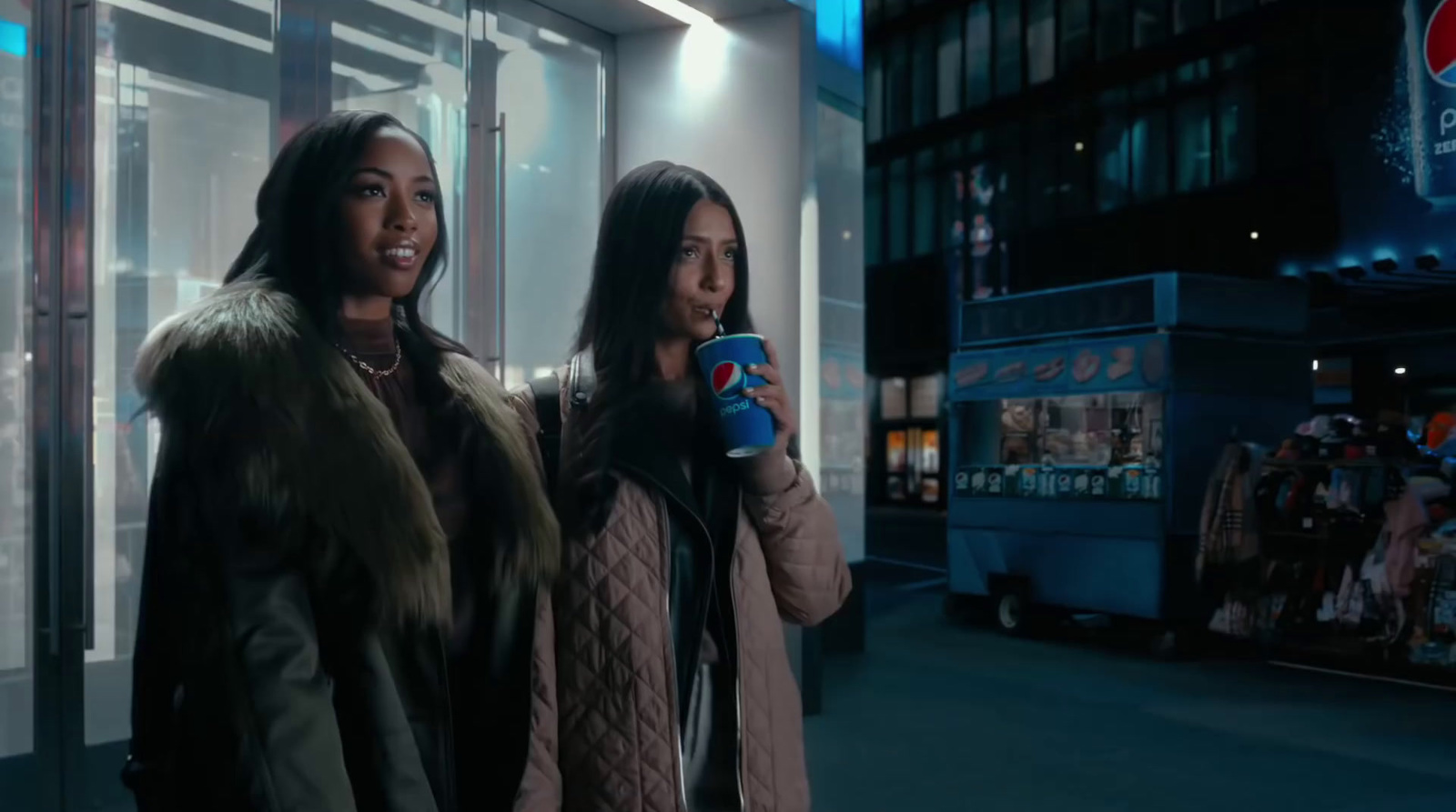 two women standing next to each other in front of a building