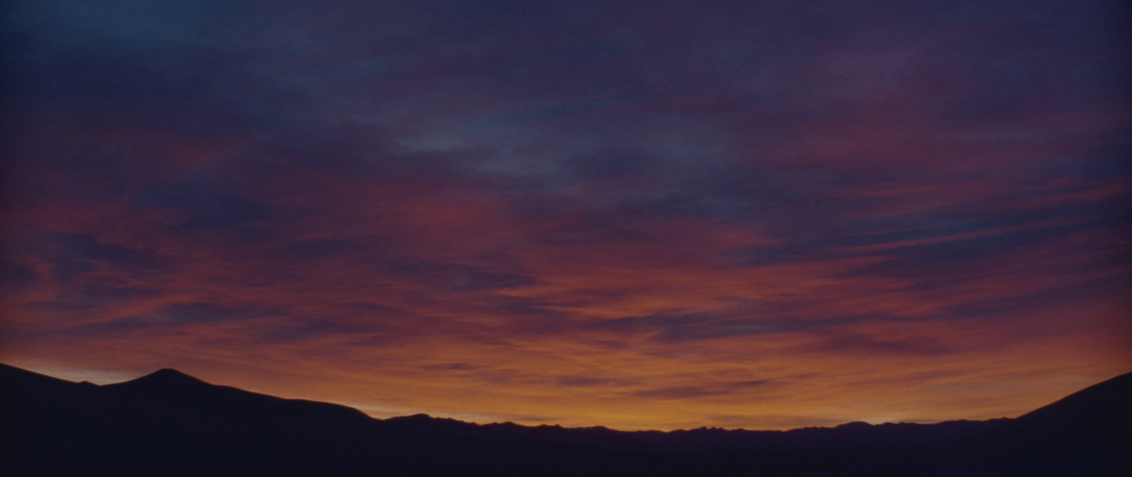 a sunset with clouds and mountains in the background