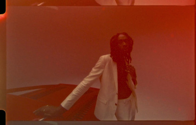 a woman with dreadlocks standing in front of a red wall