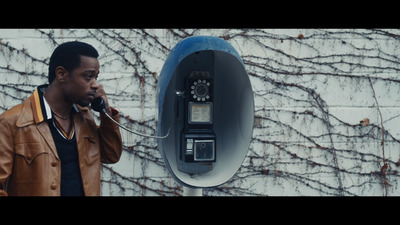 a man talking on a cell phone next to a wall