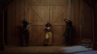 three people standing in front of a barn door