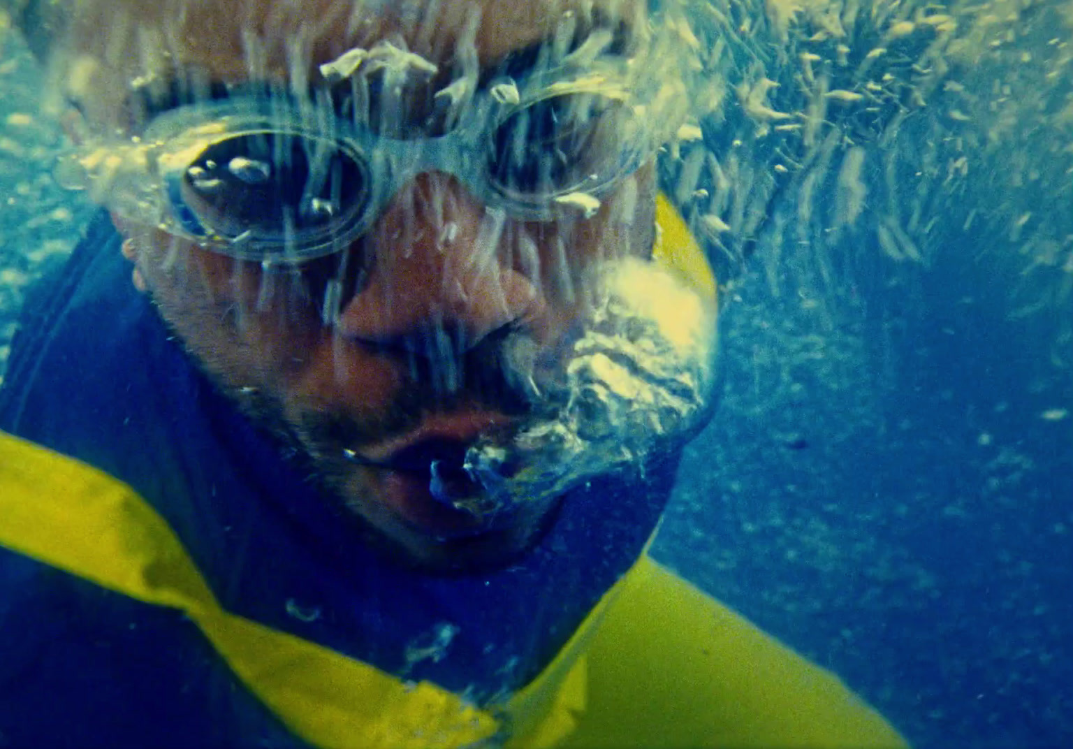 a man wearing goggles and a blue shirt under water