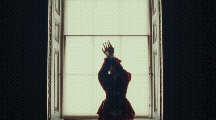 a woman standing in front of a window in a dark room