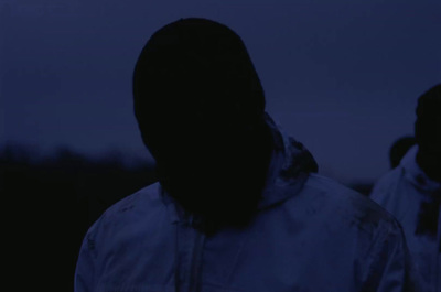 a person in a hooded jacket standing in the dark