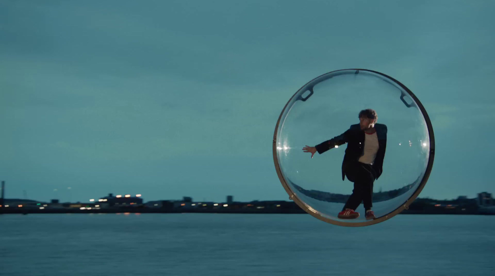 a man standing inside of a glass ball on top of a body of water