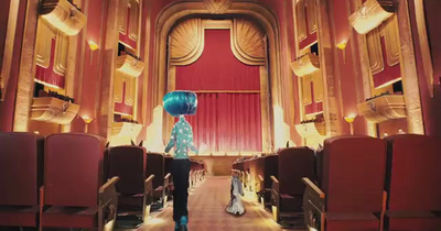 a woman with blue hair standing in front of a stage