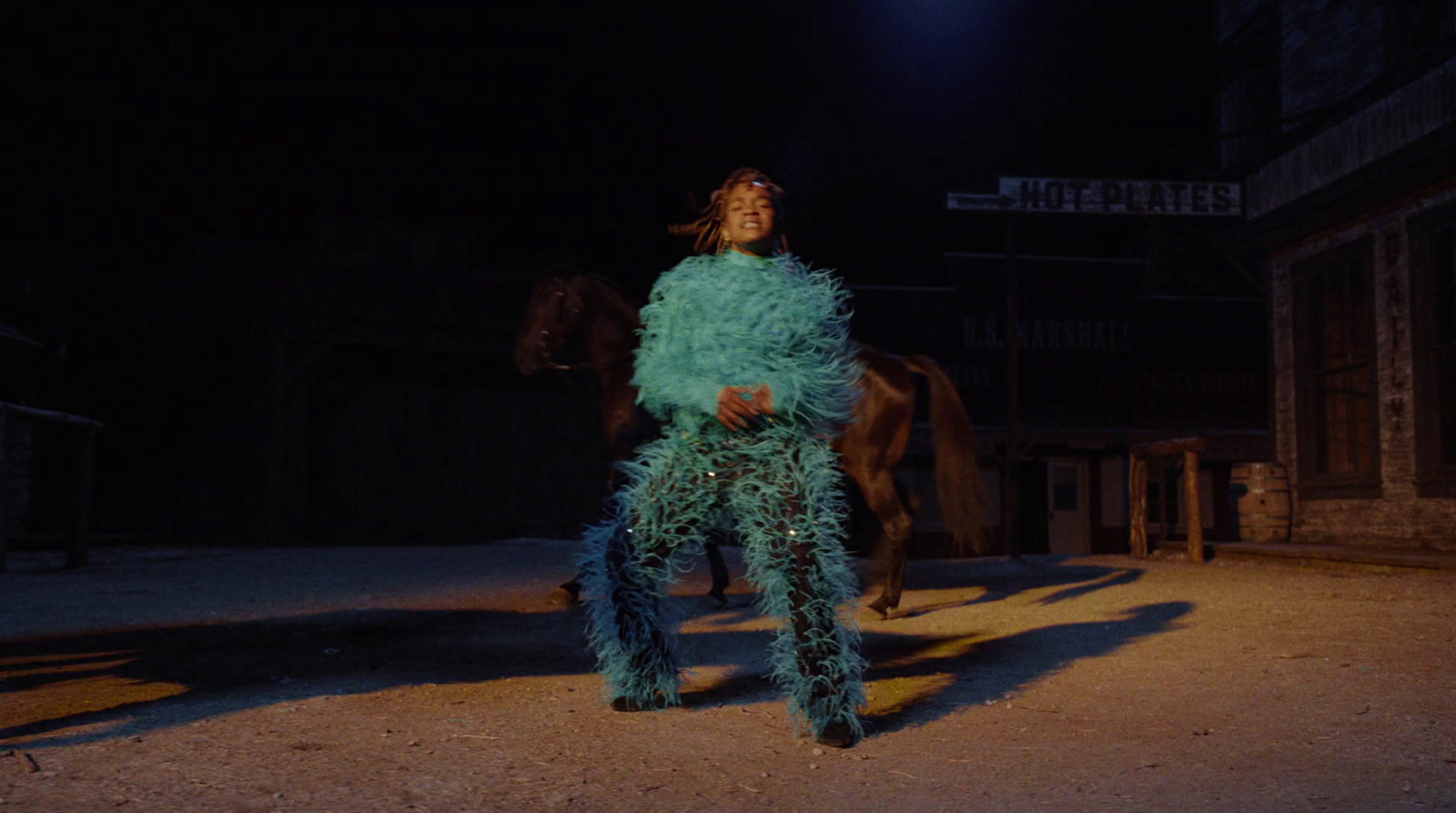 a woman in a feathery outfit standing next to a horse