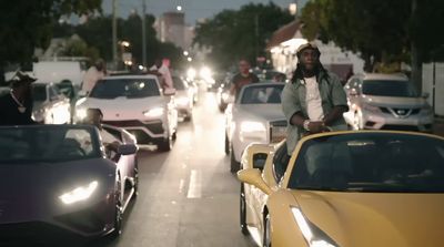 a group of cars driving down a street next to tall buildings