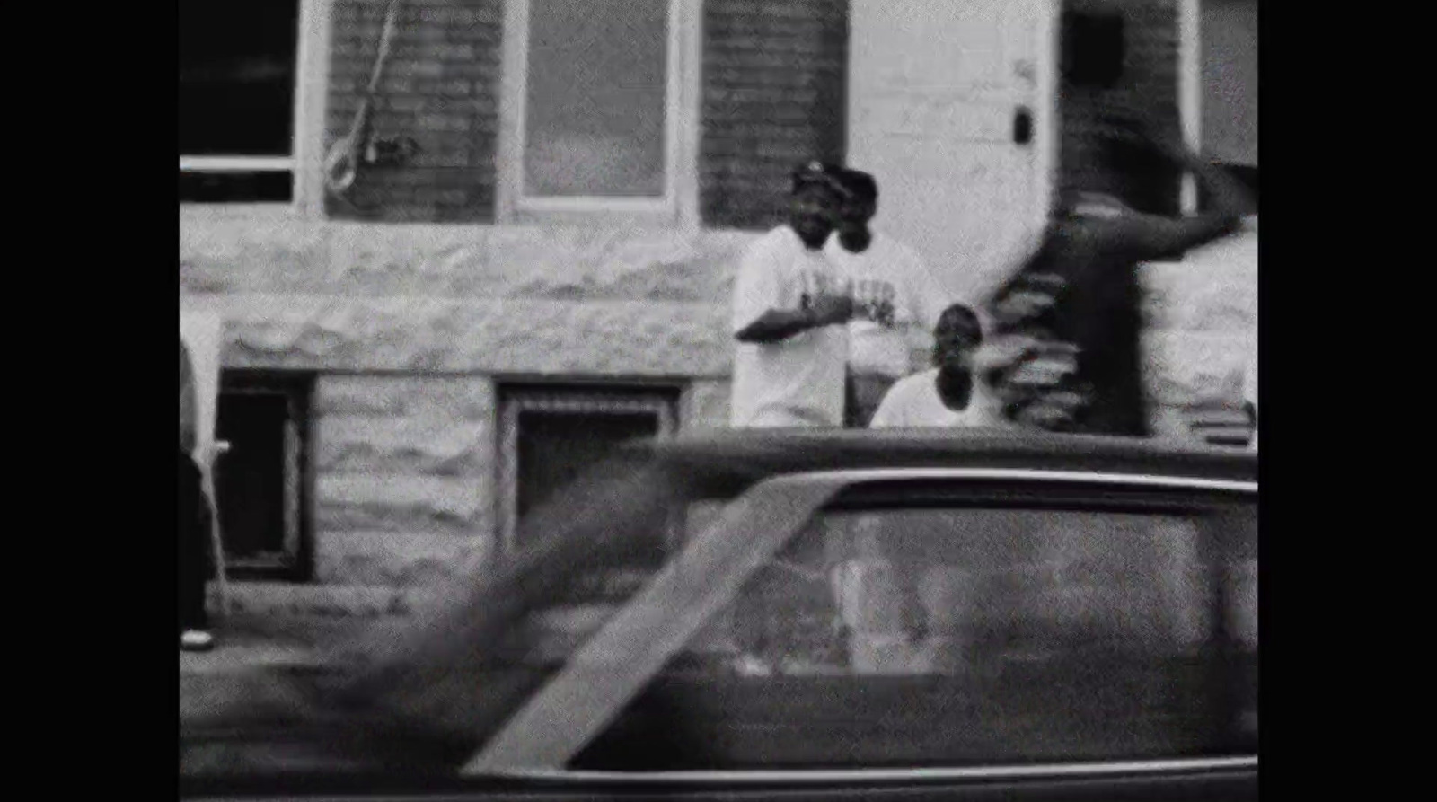 a black and white photo of a man standing next to a car