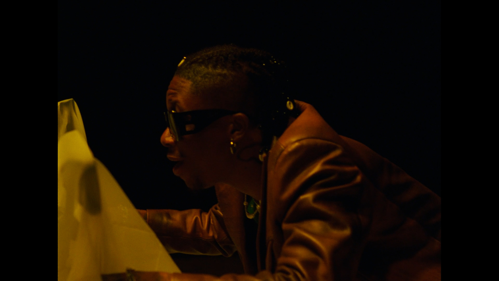 a woman in a brown jacket and sunglasses looking at a computer screen