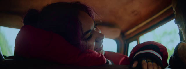 a woman in a red jacket sitting in the back of a bus