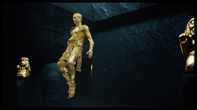 a gold statue of a woman in a dark room