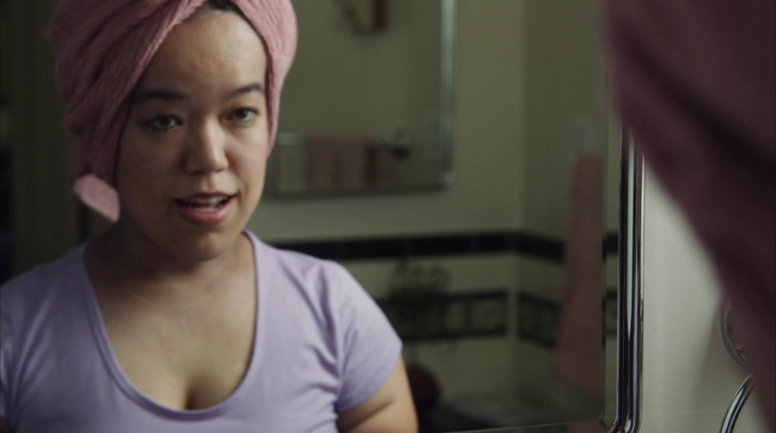 a woman with a pink towel on her head looking in a mirror