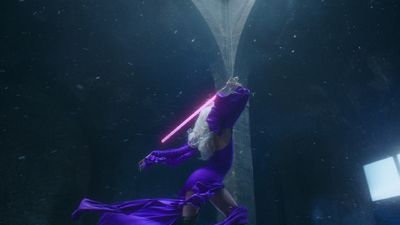 a woman in a purple dress holding a light saber