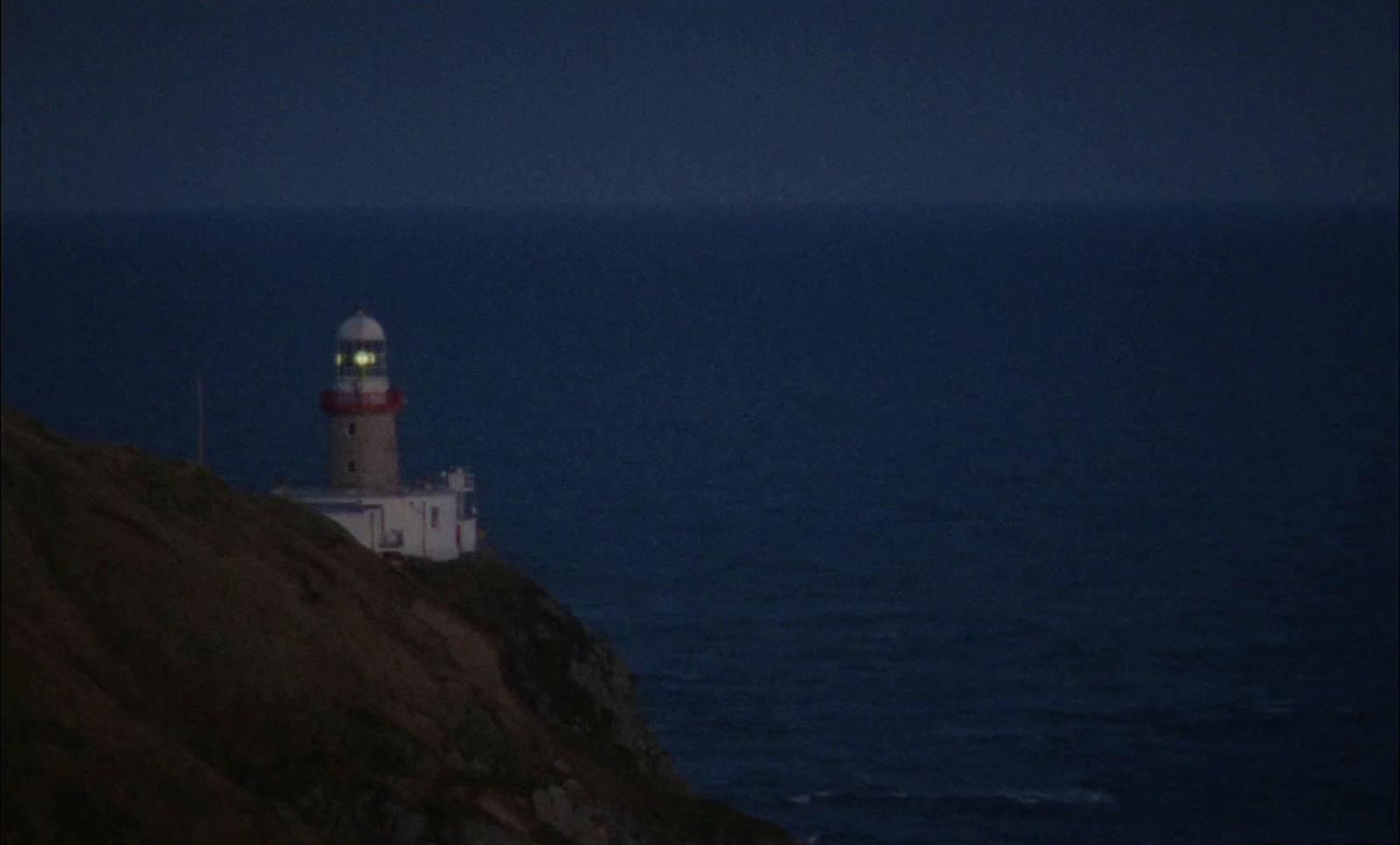 a lighthouse sitting on top of a cliff next to the ocean