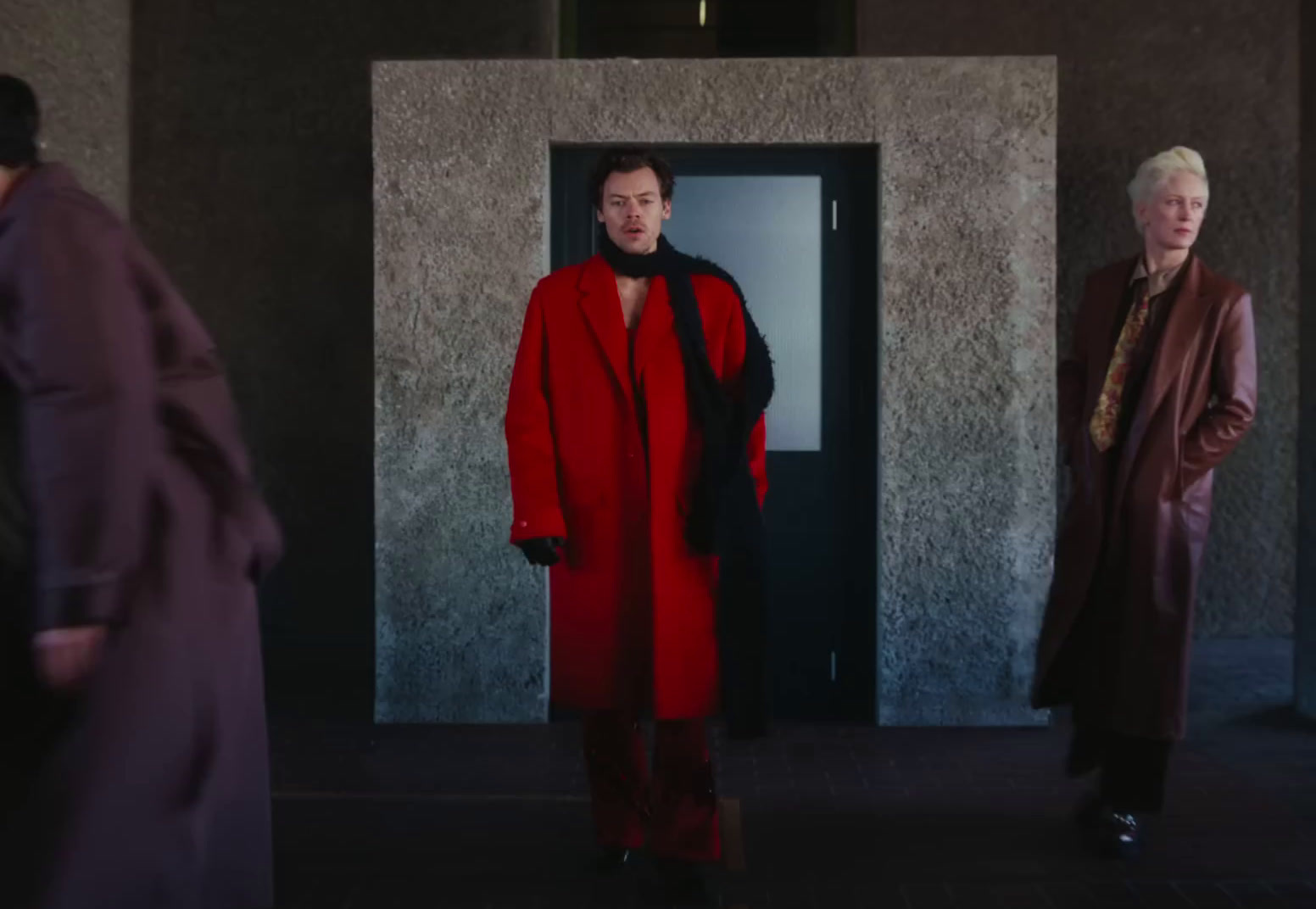 a man in a red coat standing in front of a door