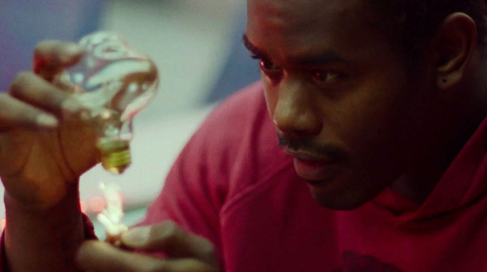 a man in a red shirt holding a glass bottle