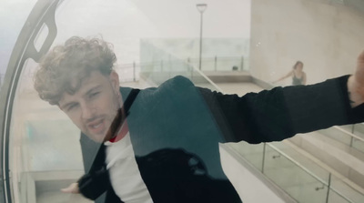 a man in a suit and tie standing in front of a window