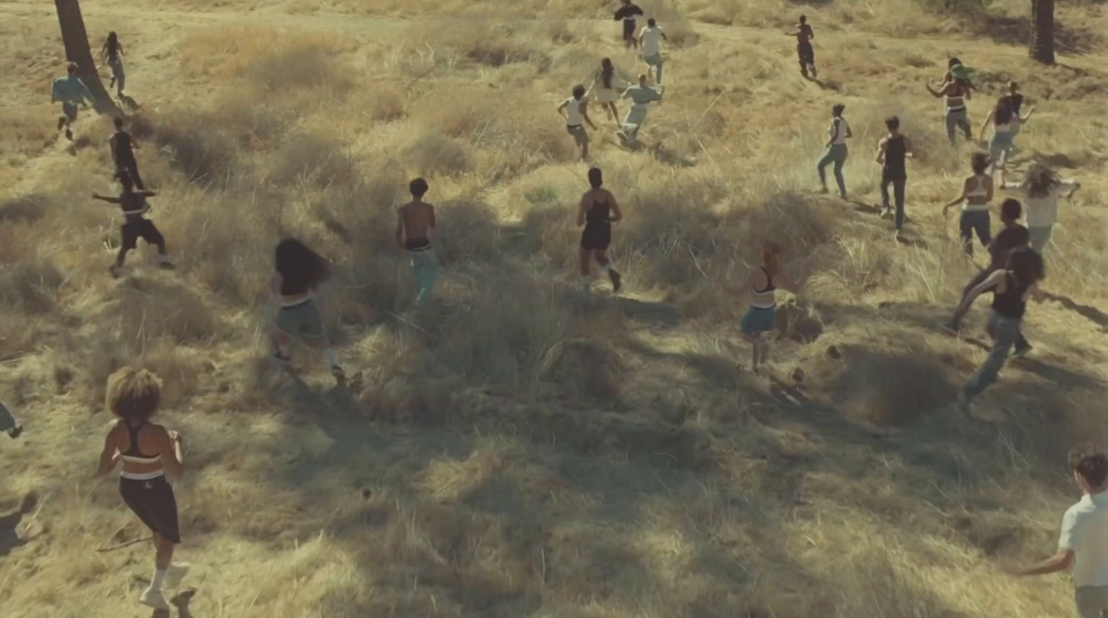 a group of people walking across a dry grass covered field