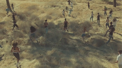 a group of people walking across a dry grass covered field