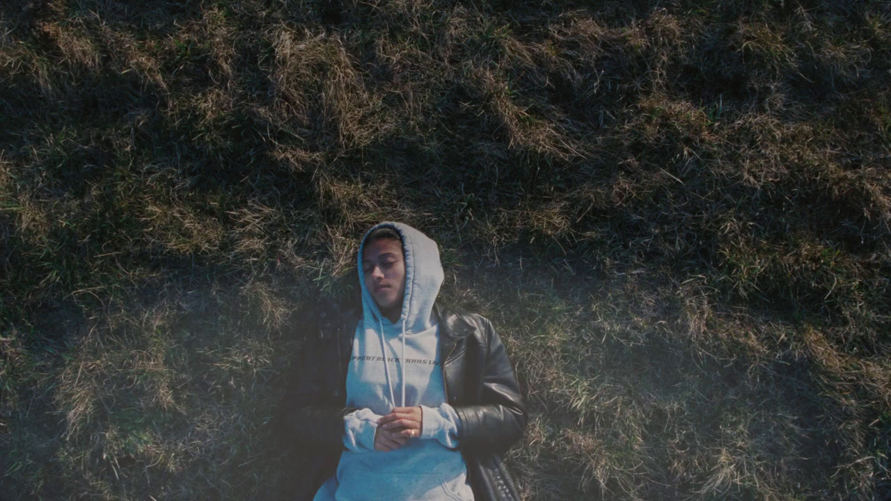 a man in a hoodie laying in the grass